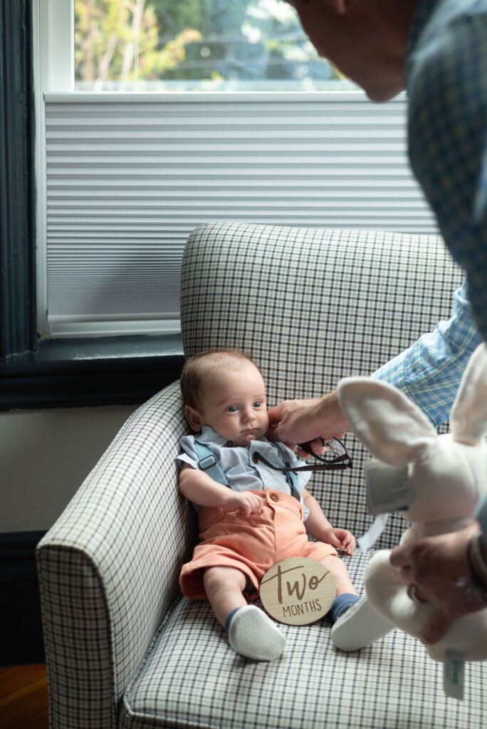 dad tenderly adjusting suspenders of baby's outfit