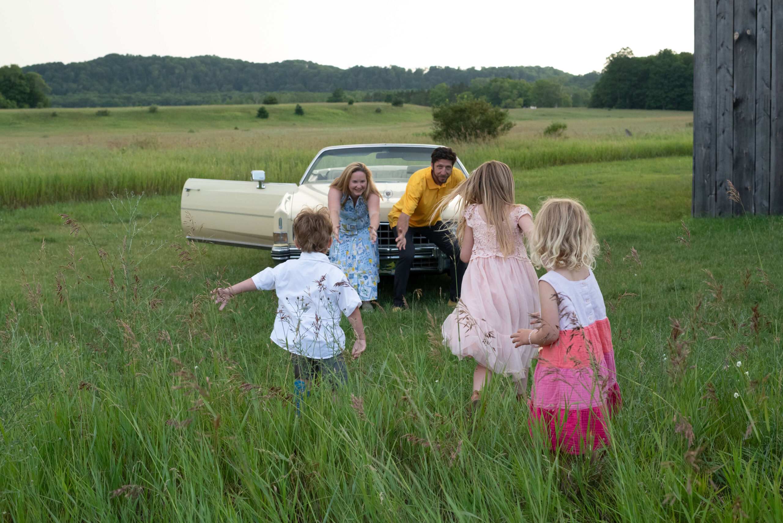 three children running toward parents with yellow 1970s cadillac in background