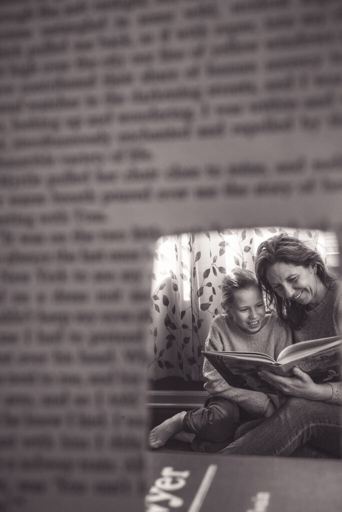 reading right now, a mother and daughter reading together viewed through a page of a book