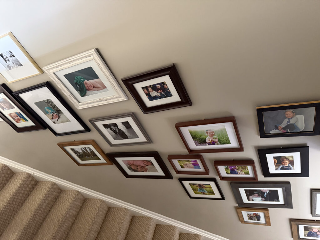 Gallery wall on staircase with mixed types of frames, sizes, and types of images