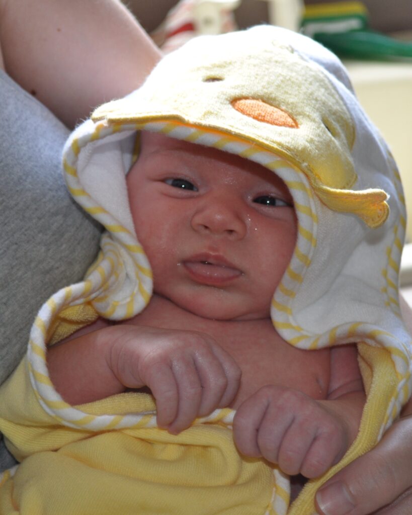 Baby wrapped in hooded towel after bath time.