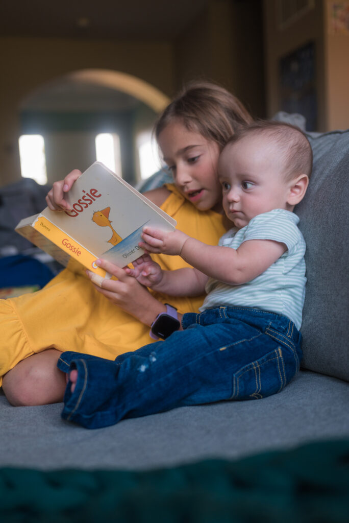 Essential baby stuff includes good books, here two children reading on a couch.