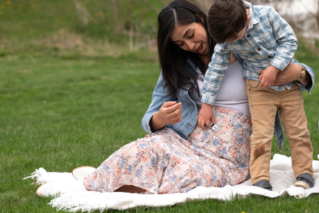 Prenatal yoga helps with connection. Pregnant mother sitting with son playing with toy car across her stomach.