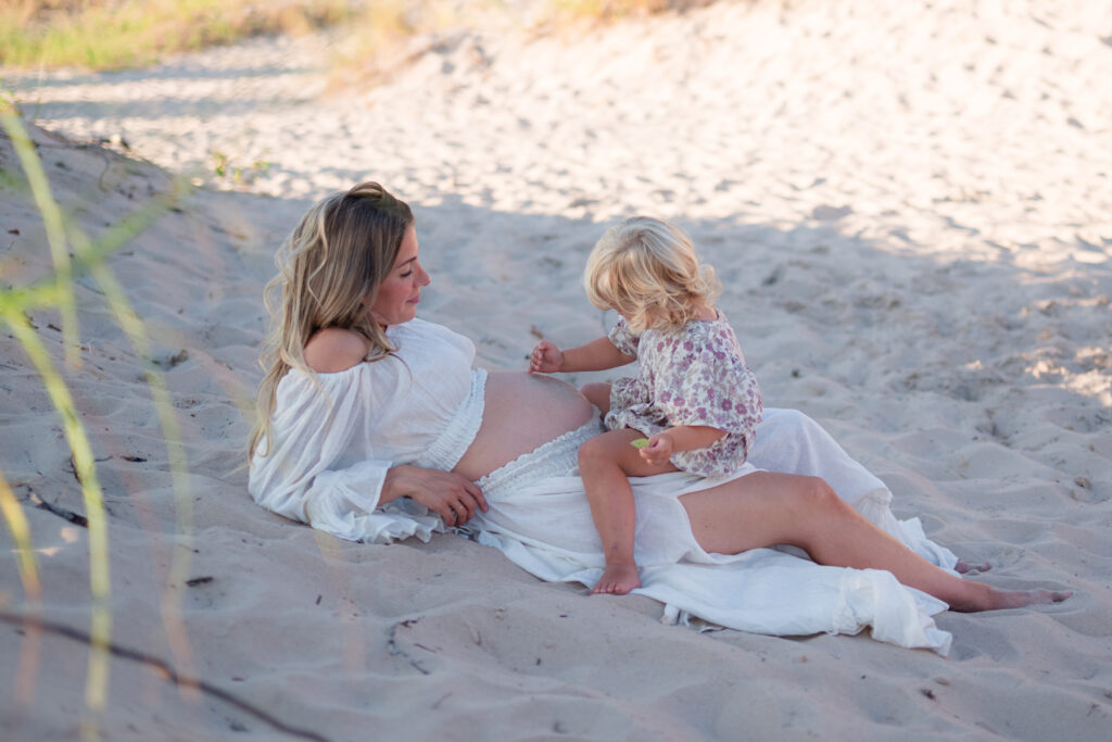 Prenatal yoga improves sleep and reduces stress. Pregnant mother connecting with her child mindfully on beach
