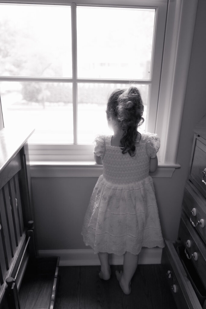 Toddler in dress having a quiet moment during an in-home newborn photo session