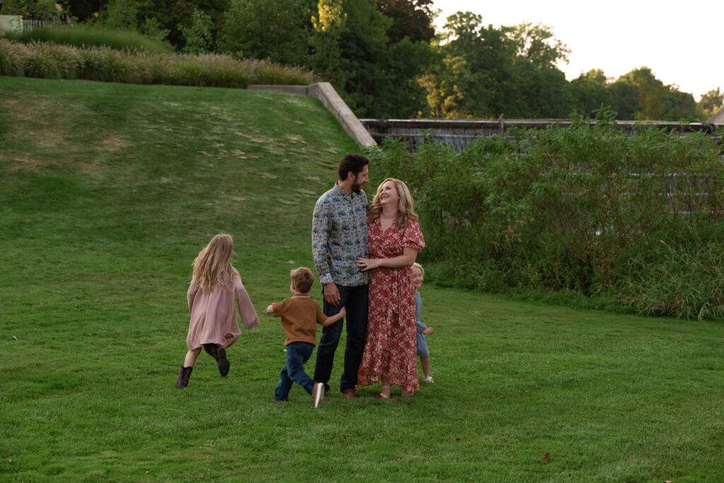 Children running playfully around parents in park.