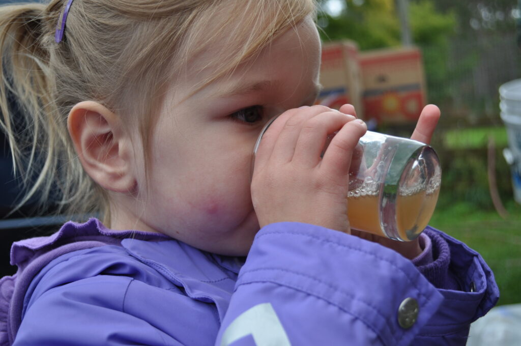 Toddler drinking apple juice from a glass cup