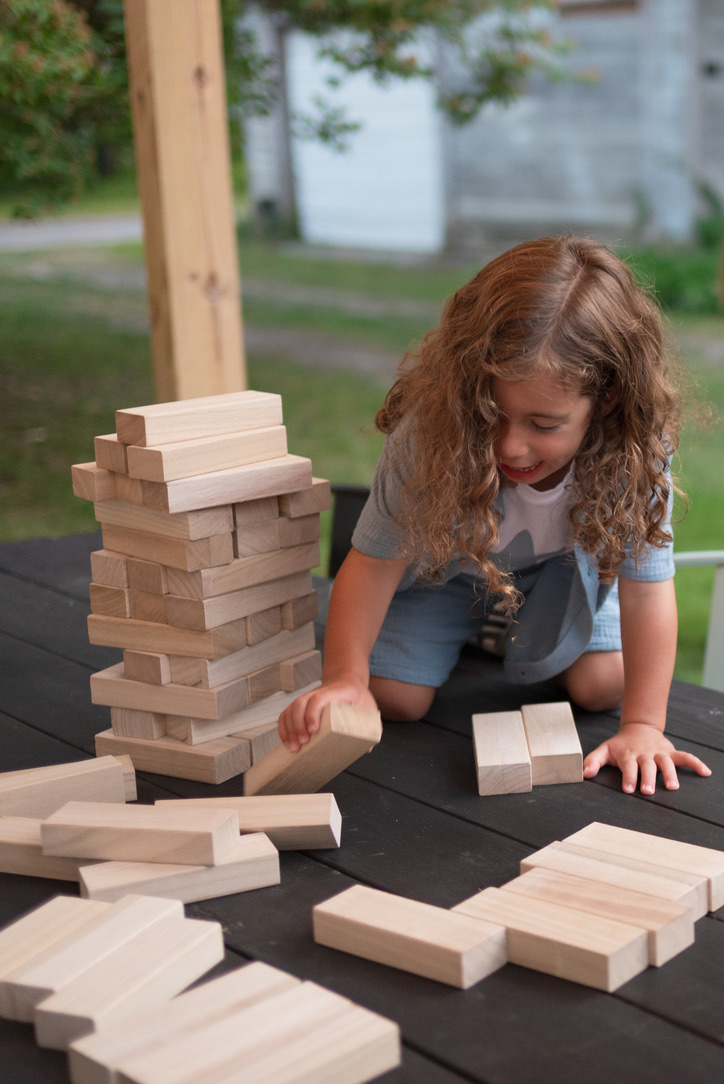 Child re-stacking the Jenga blocks all by himself during a backyard family photo session.