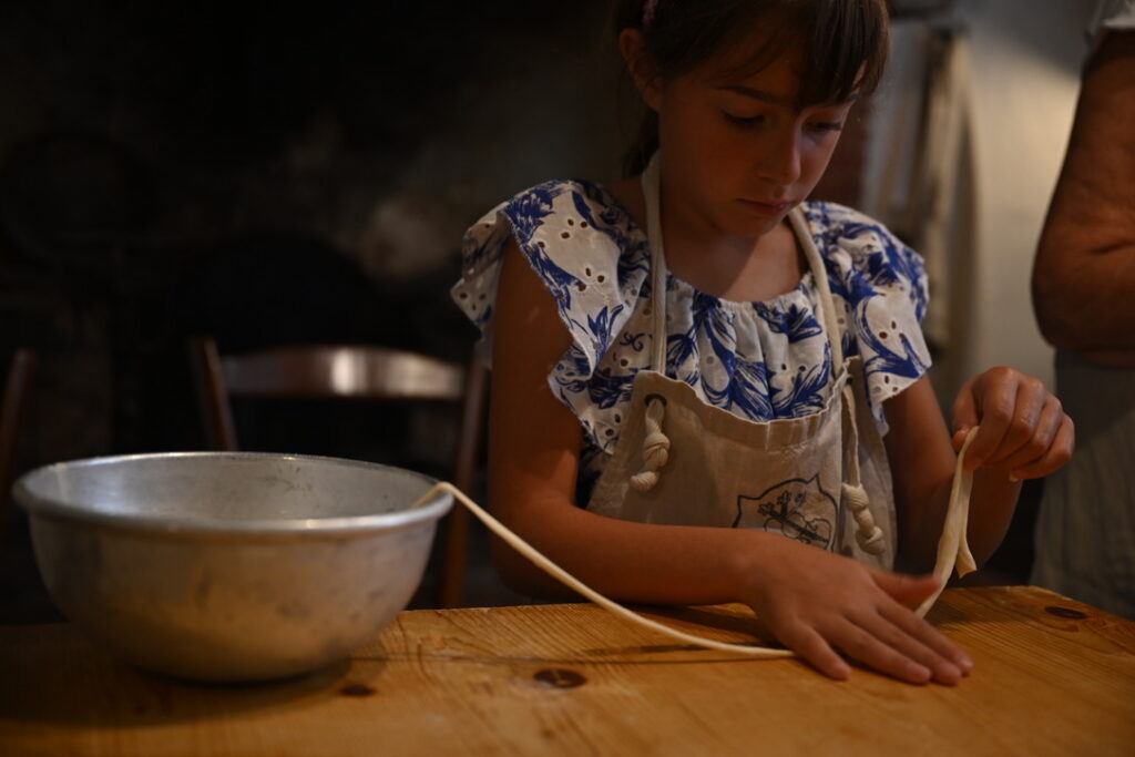 Celebrating childhood milestones like rolling pasta for a family meal independently.