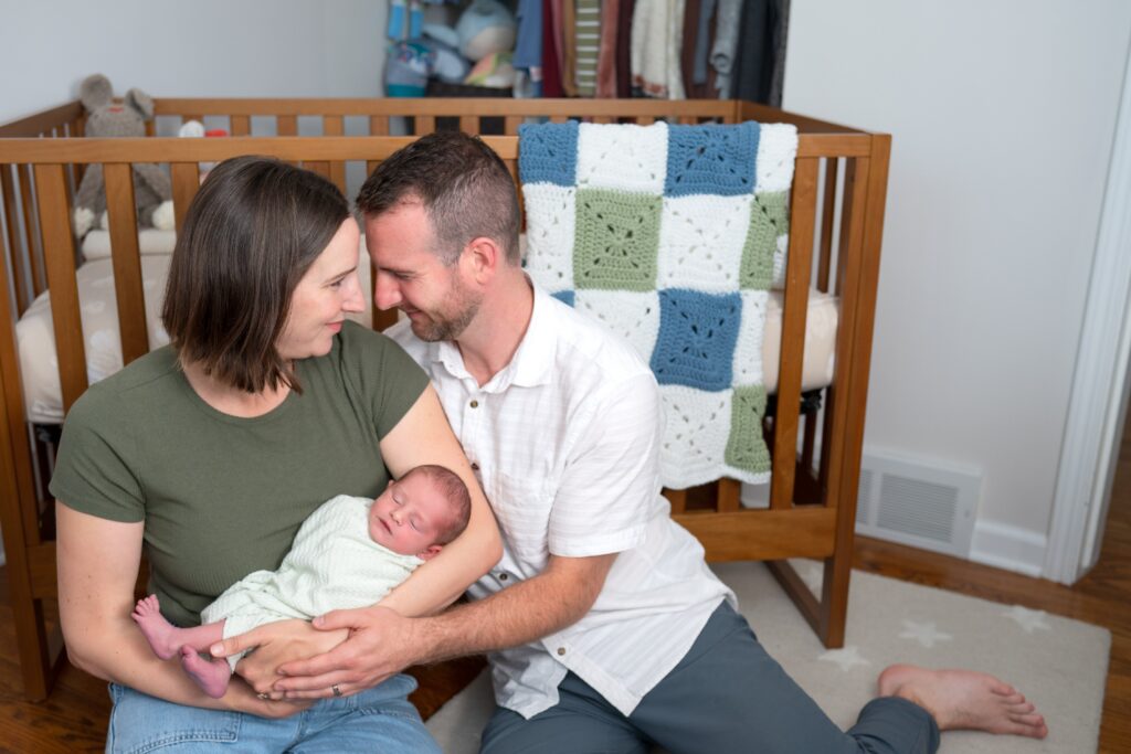 Partner in neutral textured shirt creates a coordinated comfortable style during in-home newborn session.