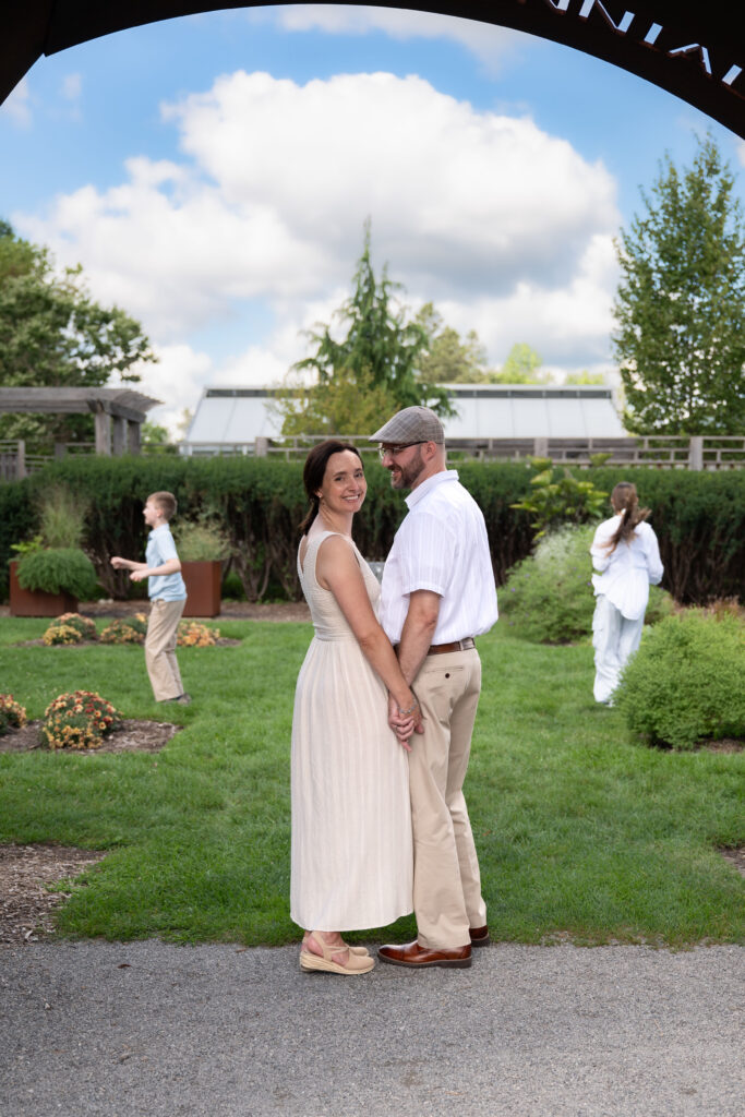 Parents enjoy a moment together at Matthaei Botanical Gardens while children play freely in the background.